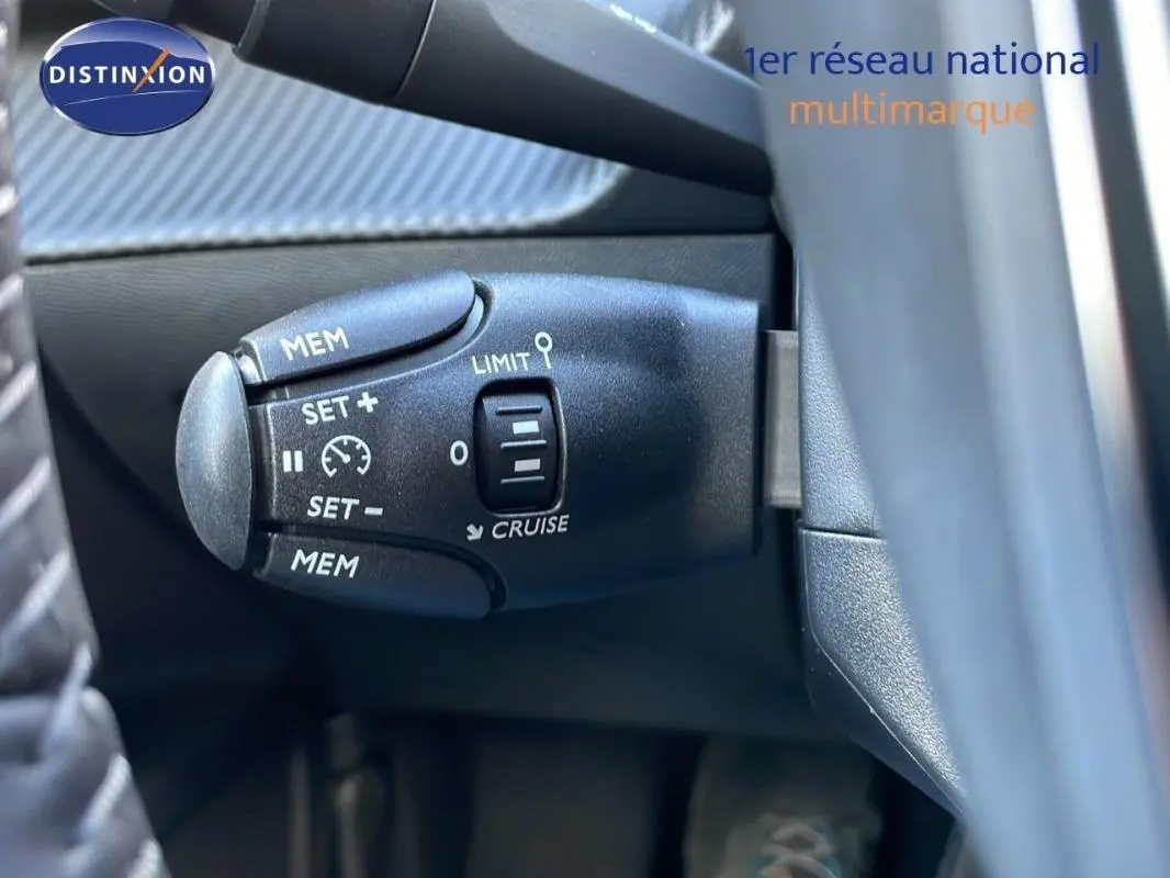 Gros plan sur la commande de régulateur de vitesse du Peugeot 2008 gris, côté gauche du volant.