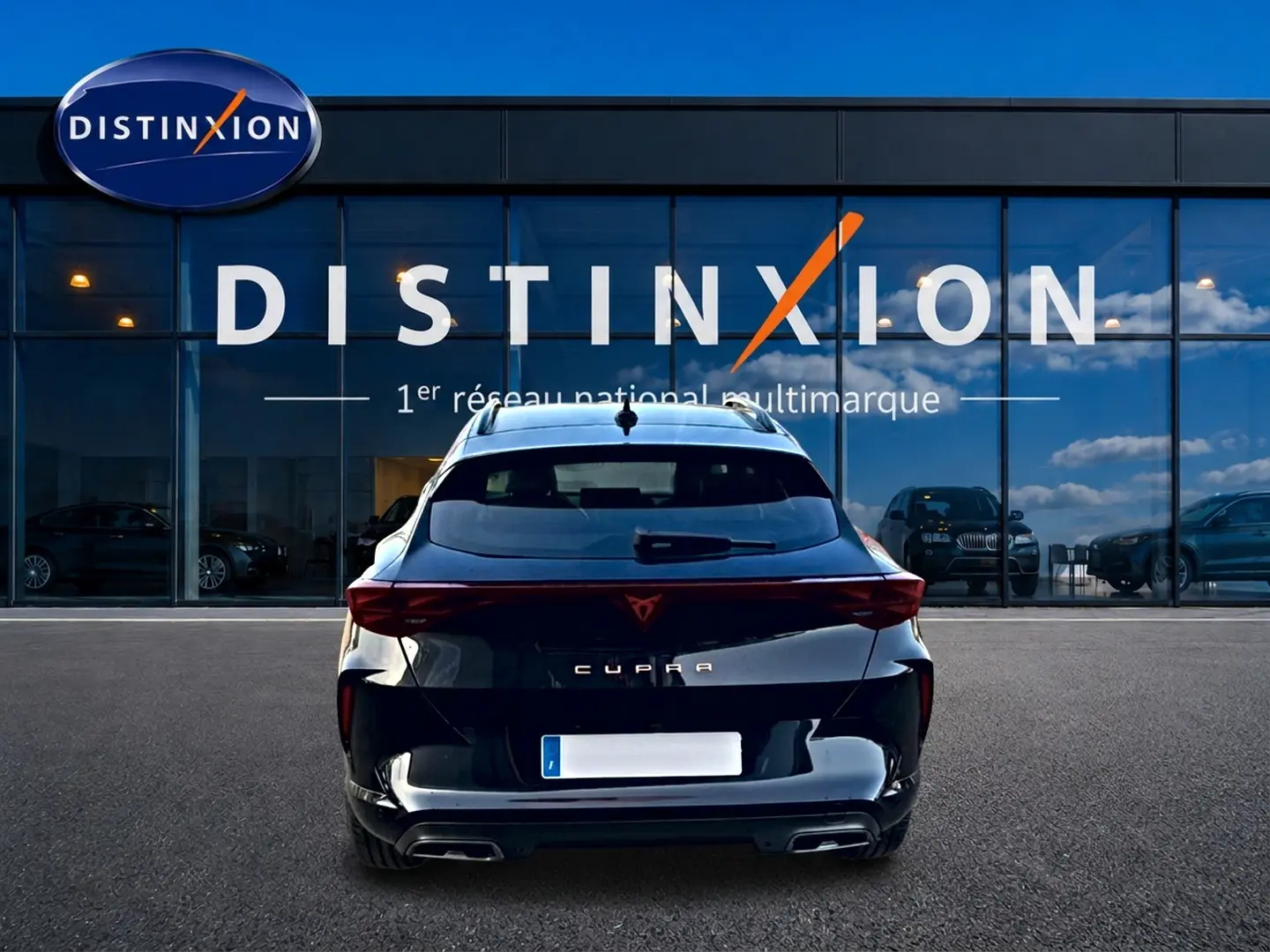 Vue arrière d'un CUPRA Formentor noir 2026 avec feux LED et double sortie d'échappement, devant une vitrine Distinxion.