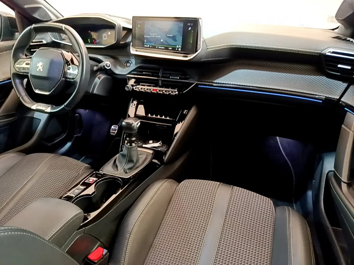 Intérieur avant droit de la Peugeot 208 GT Line 2020 avec tableau de bord noir, écran tactile et levier de vitesses manuel.
