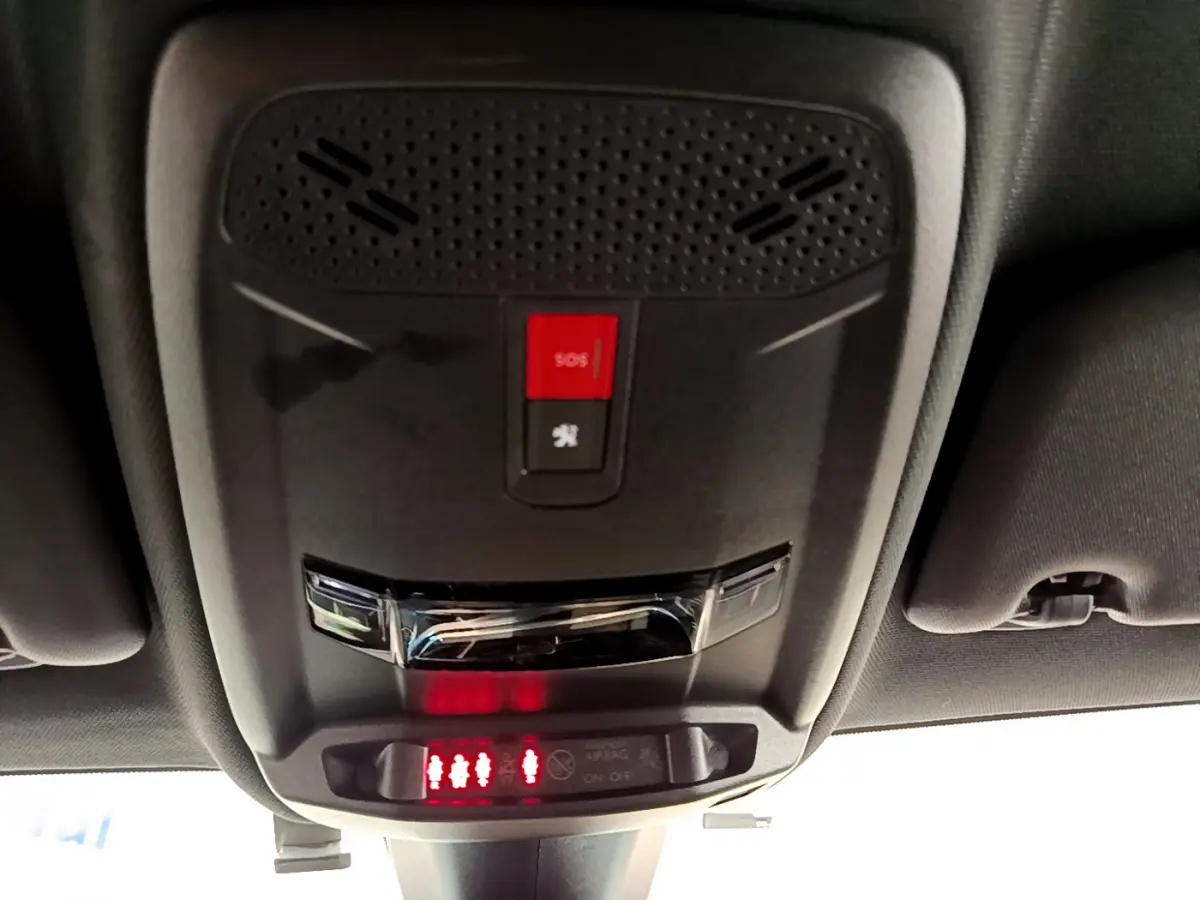 Vue en gros plan du plafonnier avec bouton SOS et indicateurs de ceintures sur le toit intérieur d'une Peugeot 208 rouge