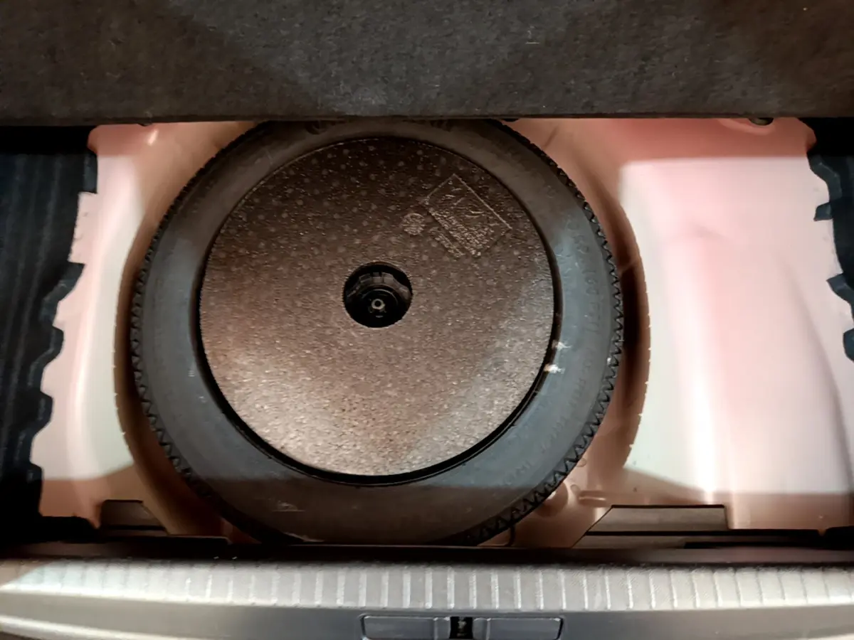 Roue de secours galette dans le coffre d'une Peugeot 208 BlueHDi 100 S&S GT Line rouge, vue en plongée.