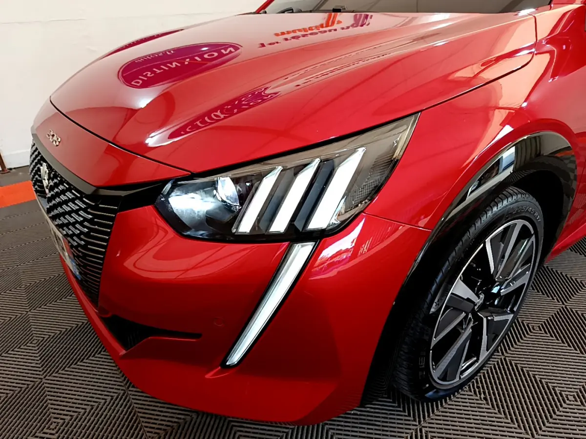 Gros plan sur l'avant droit de la Peugeot 208 GT Line rouge, mettant en valeur ses phares LED et sa calandre distinctive.
