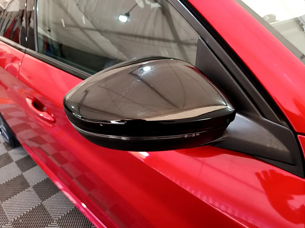 Rétroviseur noir côté gauche sur la porte rouge vif d'une Peugeot 208 GT Line 2020 vue en gros plan.