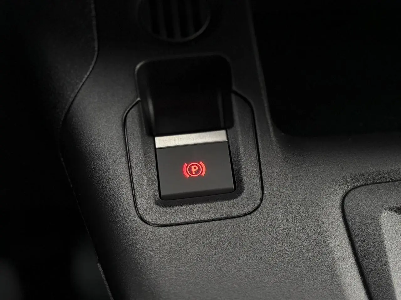 Gros plan sur le bouton de frein de stationnement électrique rouge dans l'habitacle du Citroën Berlingo blanc Icy 2025.