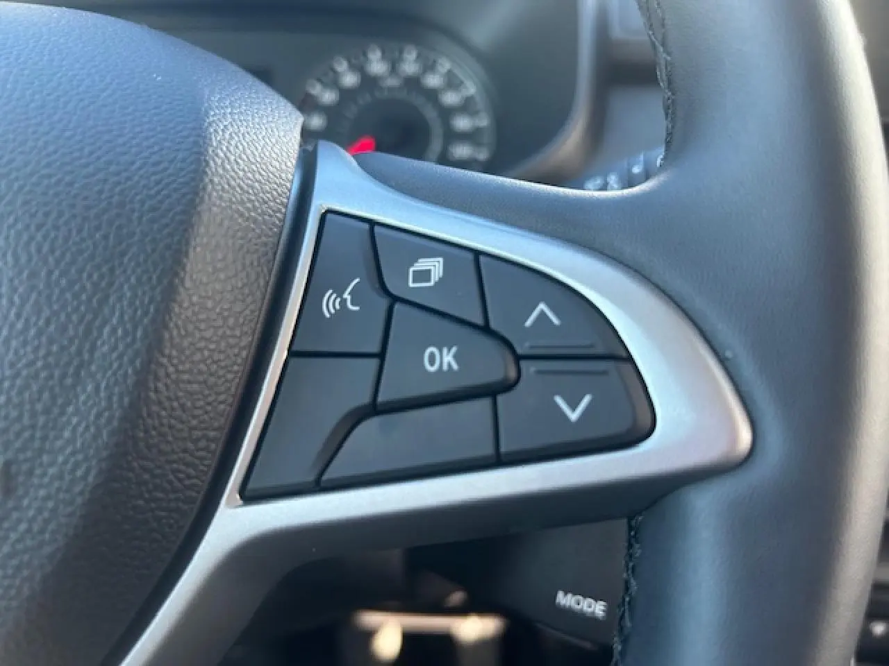 Gros plan sur les commandes multifonctions noires et argent du volant cuir noir du Dacia Sandero III Stepway beige Safari.