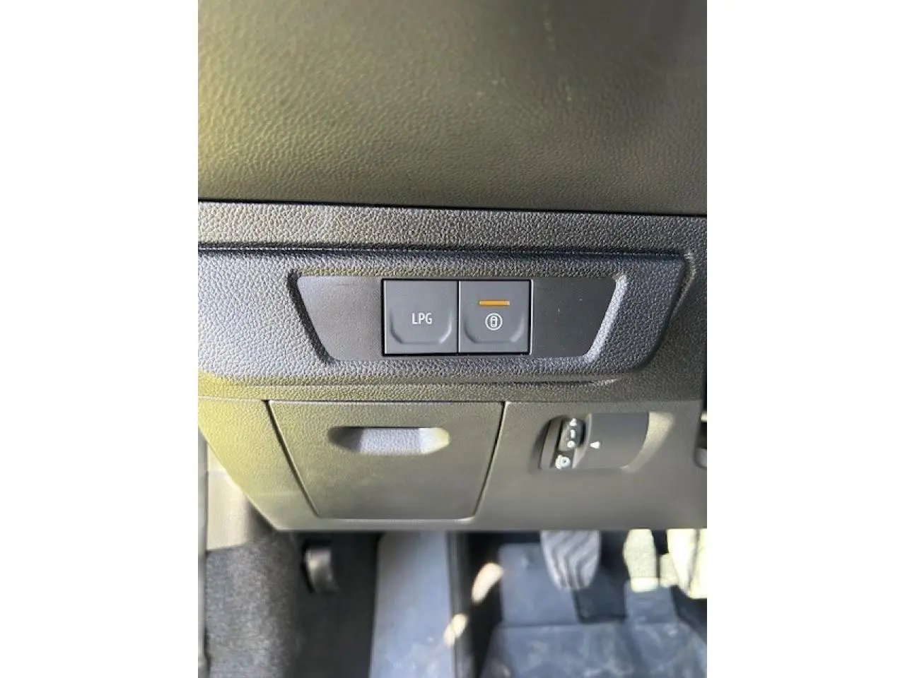 Détail intérieur montrant les boutons de commande LPG et verrouillage sous le tableau de bord noir du Dacia Sandero Stepway beige.