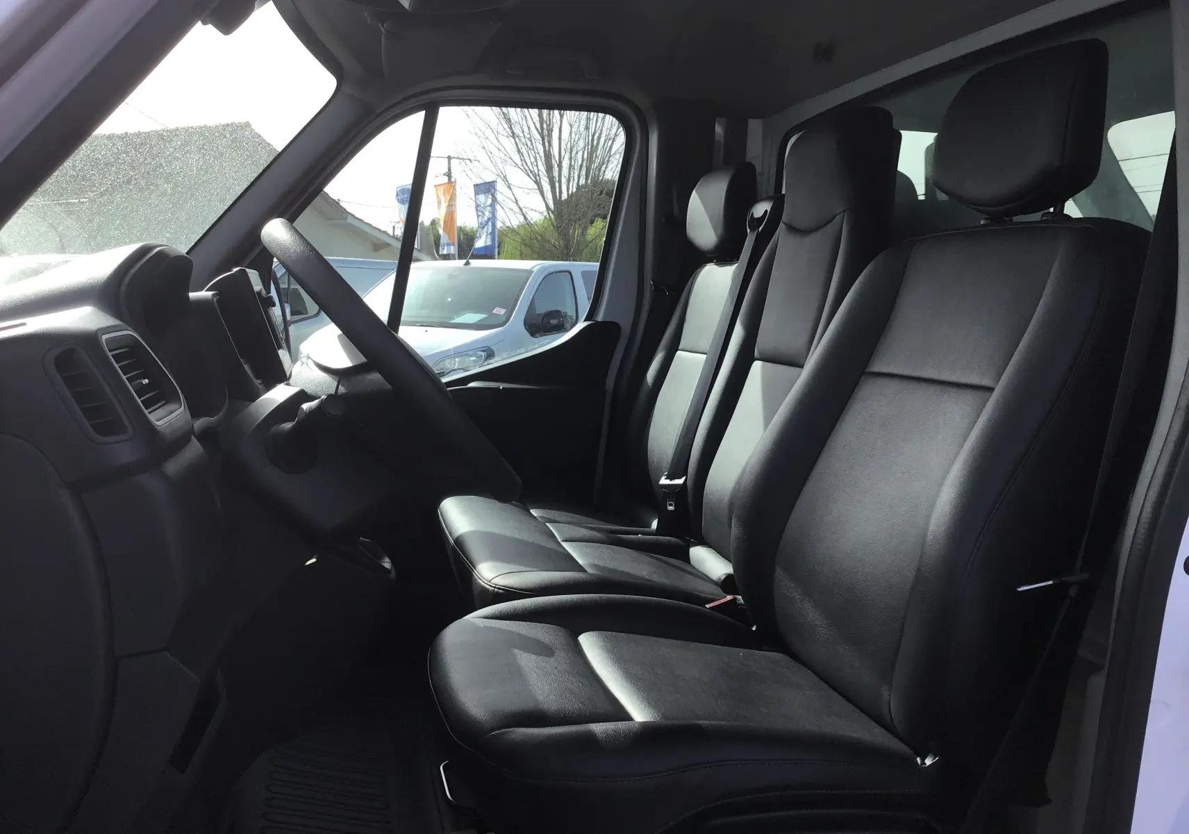 Intérieur de l'Opel Movano Chassis Cabine blanc, vue latérale des sièges avant en cuir noir et tableau de bord.