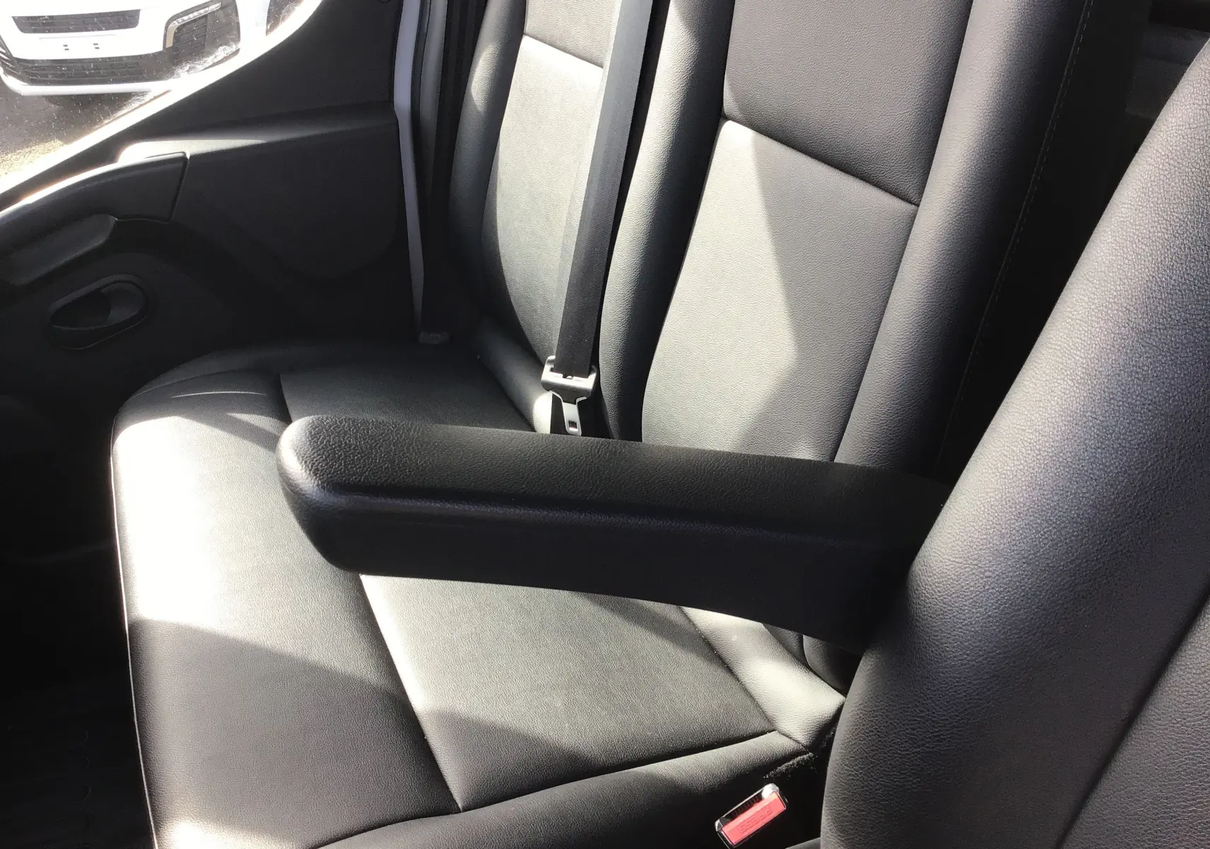 Gros plan sur les sièges avant en cuir noir de l'Opel Movano Châssis Cabine blanc, avec accoudoir central visible.