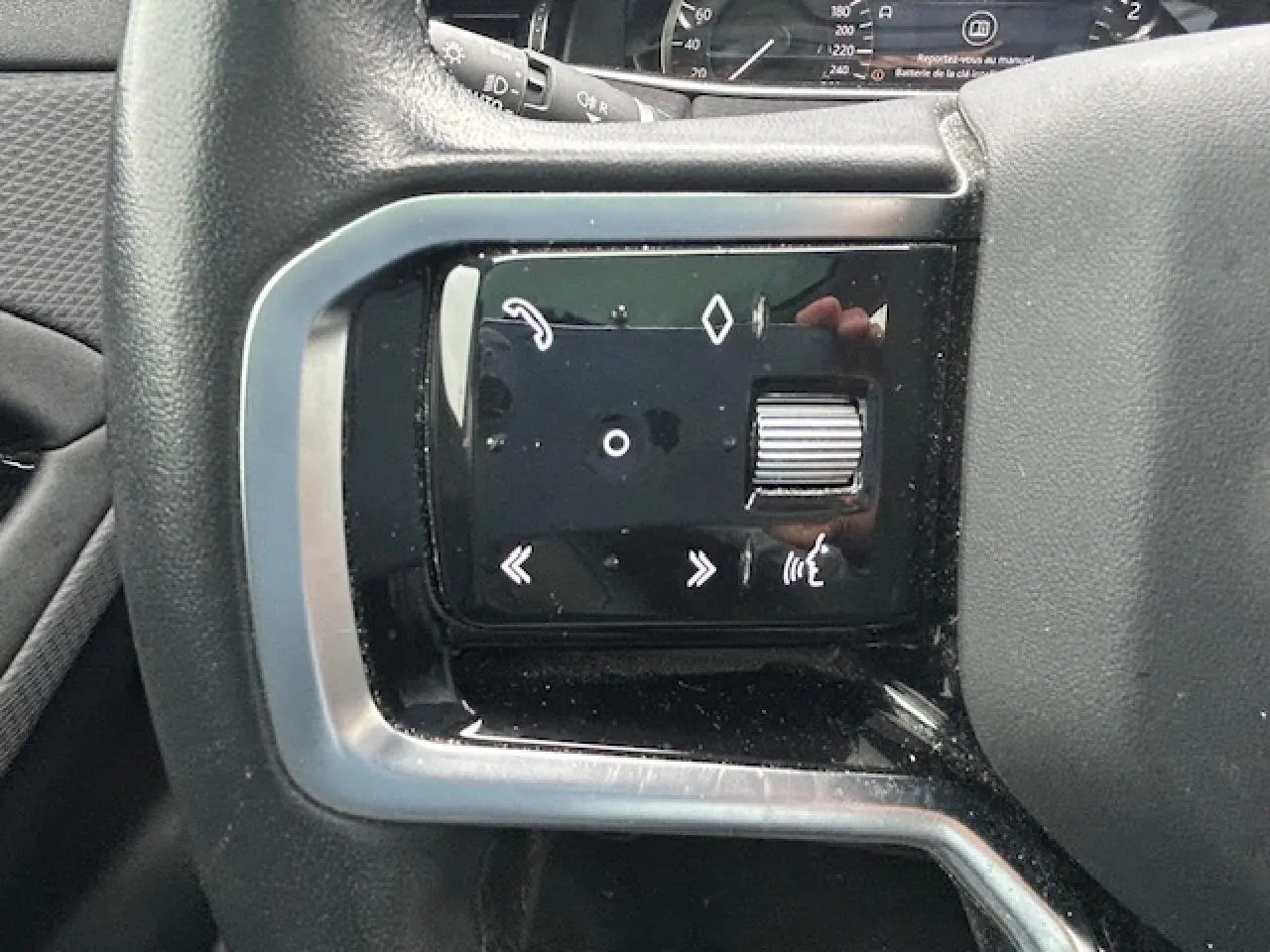 Gros plan sur les commandes multifonctions noires à gauche du volant du Range Rover Evoque gris foncé 2022.