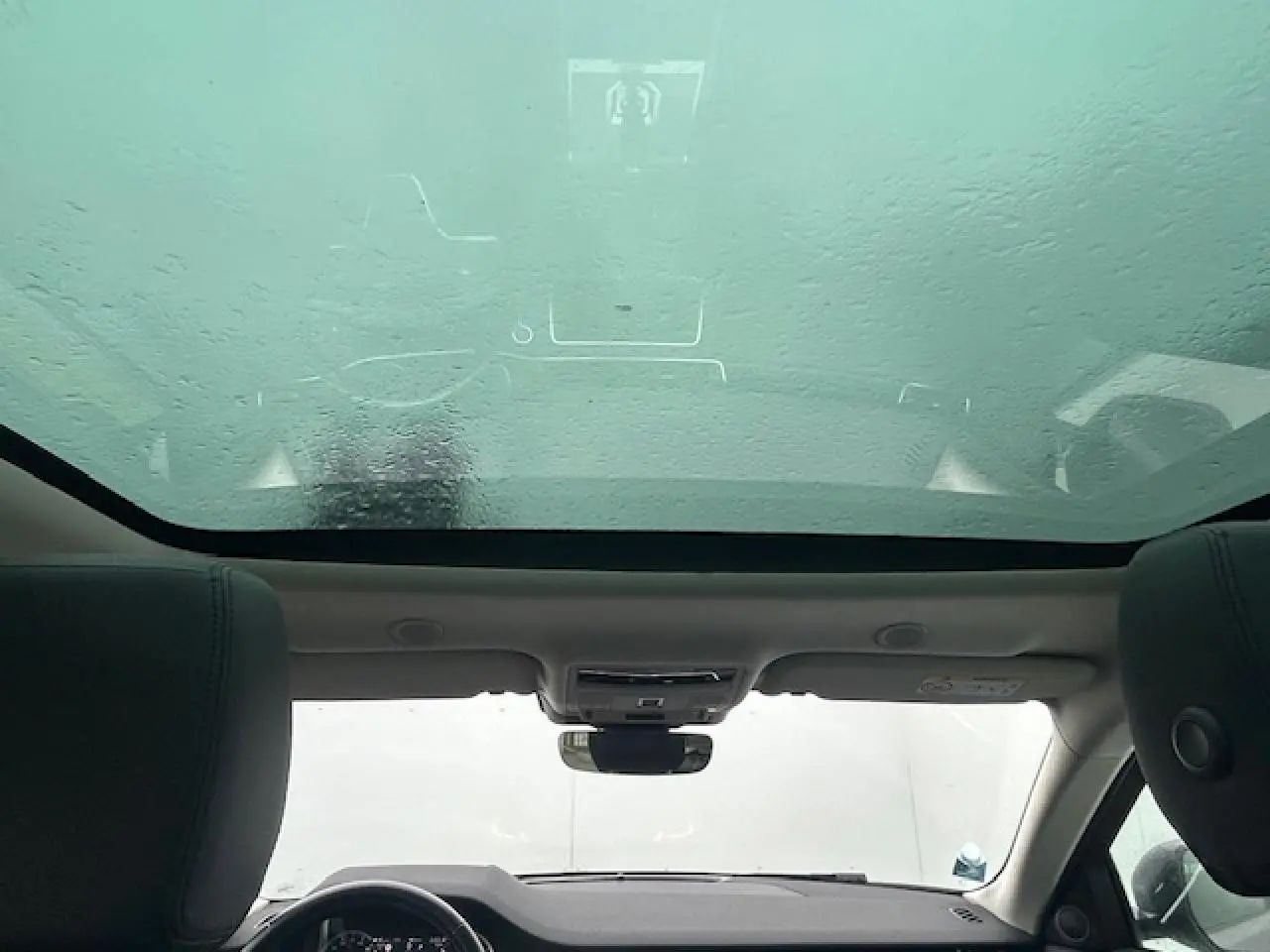 Vue intérieure du Range Rover Evoque gris foncé, mettant en valeur le toit panoramique fixe et le tableau de bord.