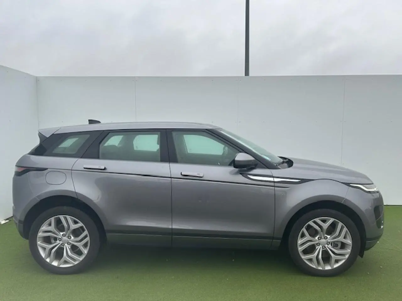 Profil droit du Range Rover Evoque gris foncé métal avec jantes 20 pouces et lignes épurées modernes.