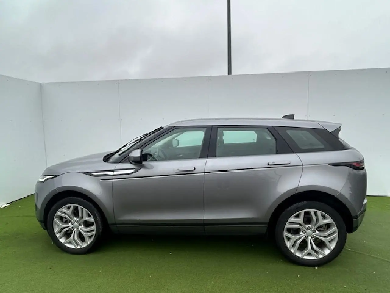 Range Rover Evoque gris foncé métallisé vu de profil côté gauche, avec jantes 20 pouces et toit noir contrasté.