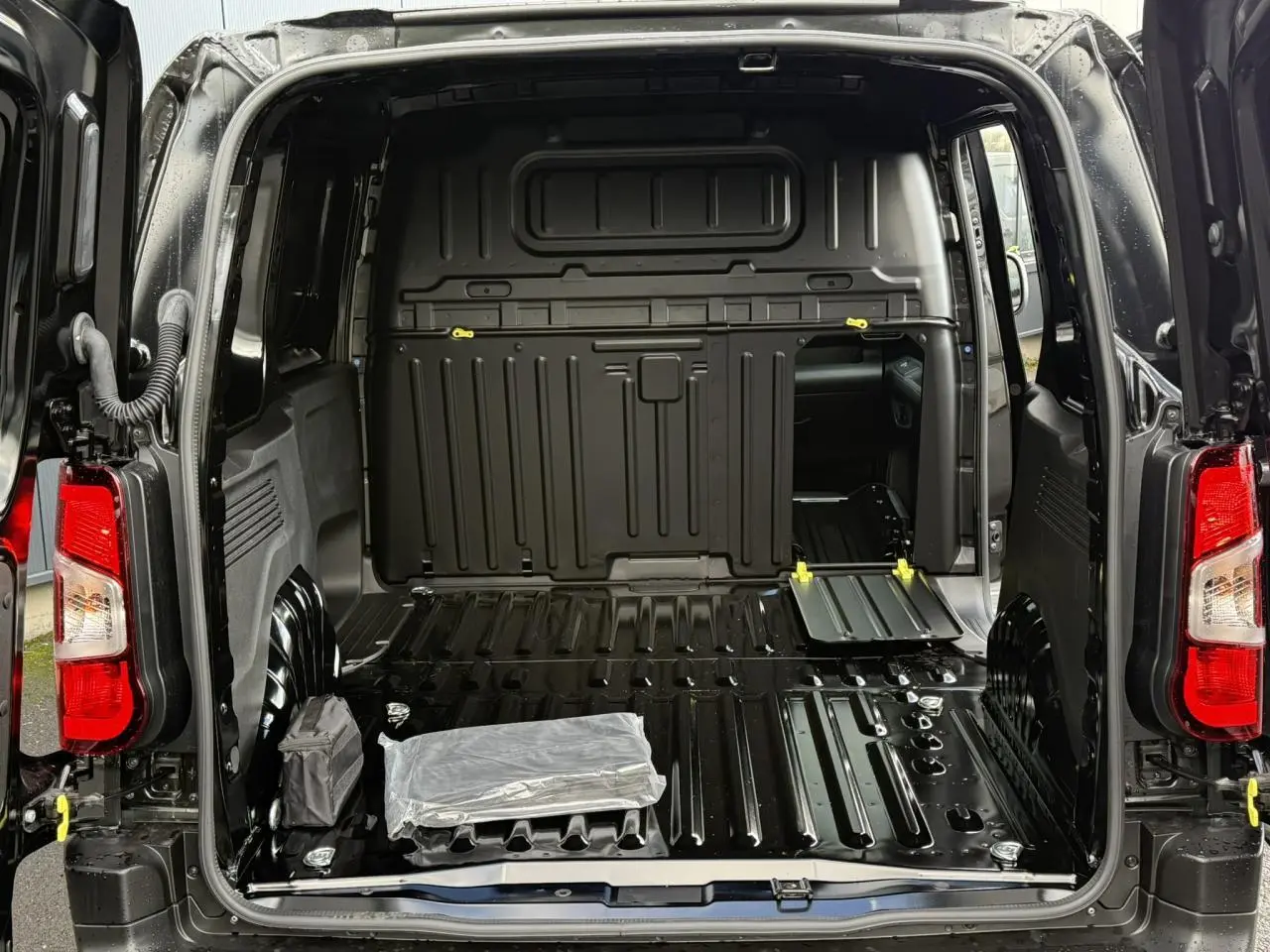 Vue arrière ouverte du Citroën Berlingo Van noir Perla, montrant l'espace de chargement tôlé et la cloison fixe.