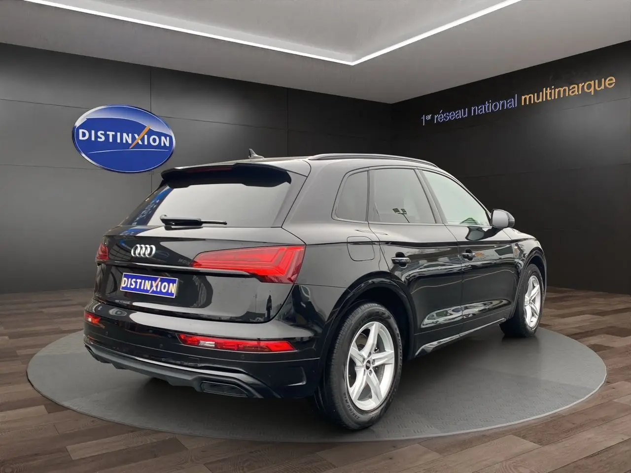Audi Q5 noir vue 3/4 arrière droit, avec feux LED et jantes alliage cinq branches visibles en showroom.