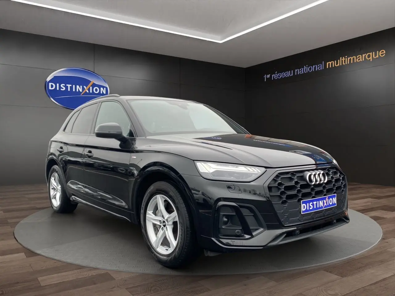 Audi Q5 Business Edition S-Line noir, vue 3/4 avant droit, avec calandre hexagonale et phares LED distinctifs.