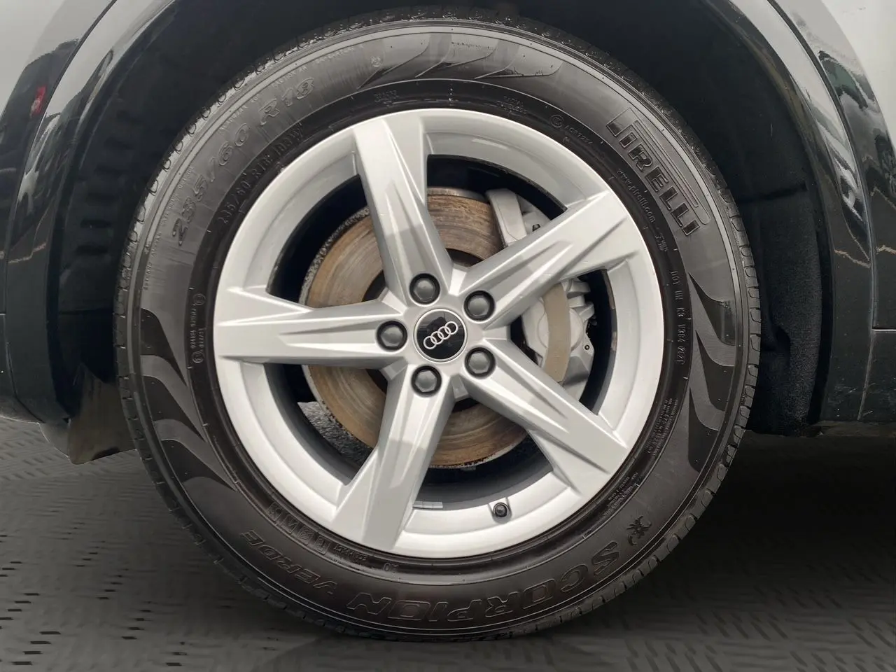 Gros plan sur la roue avant droite noire d’un Audi Q5 2022 avec jante alliage argentée à cinq branches.