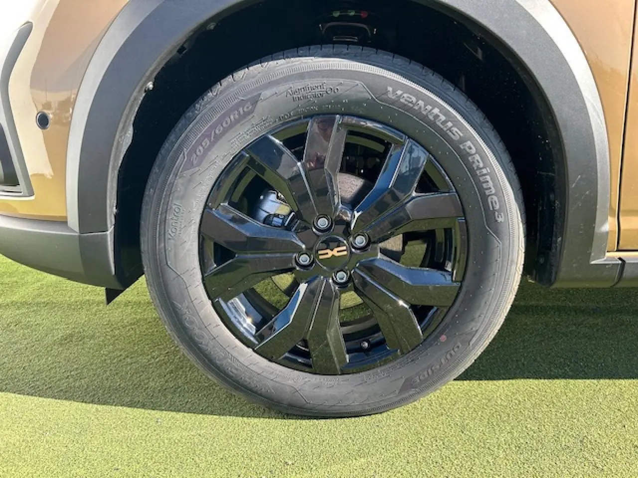 Gros plan sur la roue avant droite noire brillante du Dacia Sandero Stepway beige Safari avec jante aluminium 16 pouces.