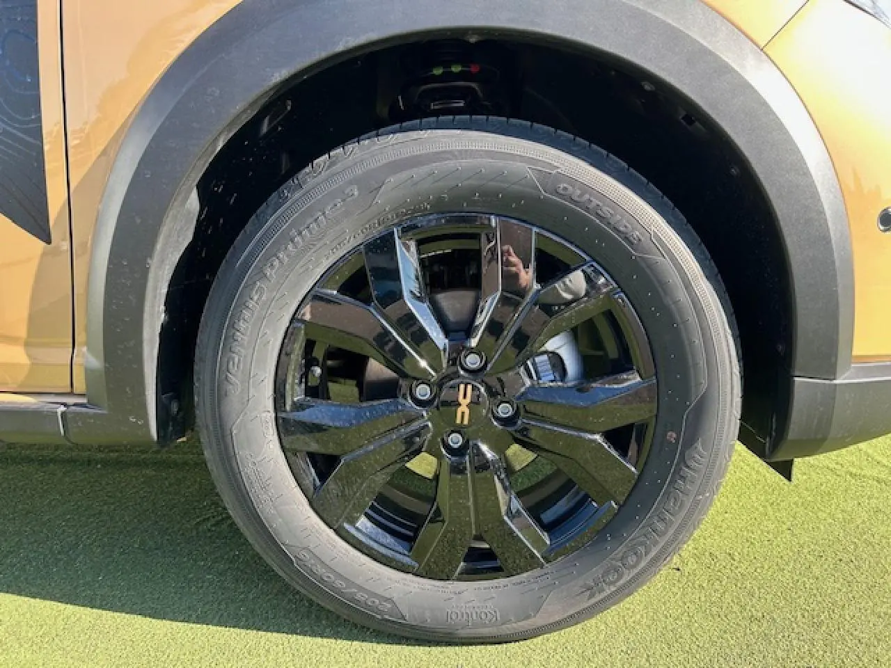 Gros plan sur la roue arrière droite noire brillante avec logo Stepway sur un Dacia Sandero beige Safari.