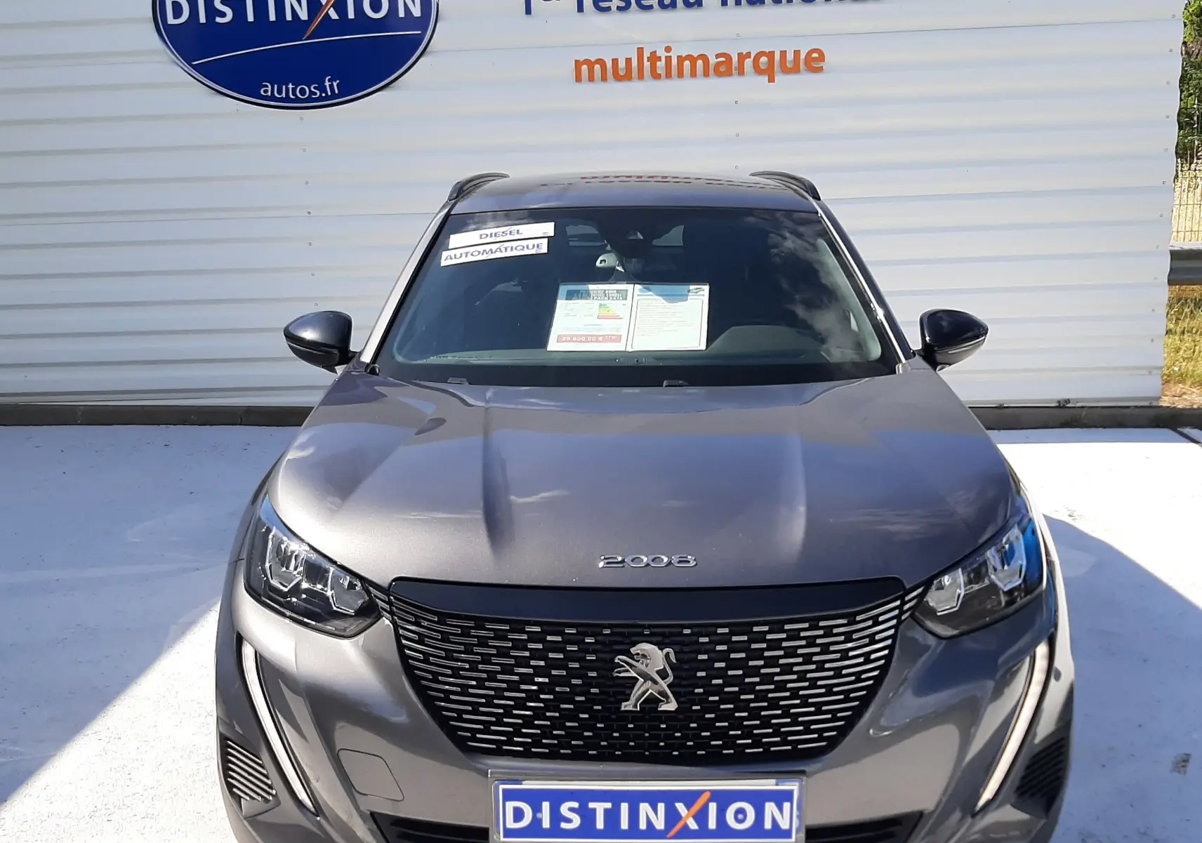 Vue frontale d'un Peugeot 2008 gris platinium 2023 avec calandre noire et logo lion distinctif visible.