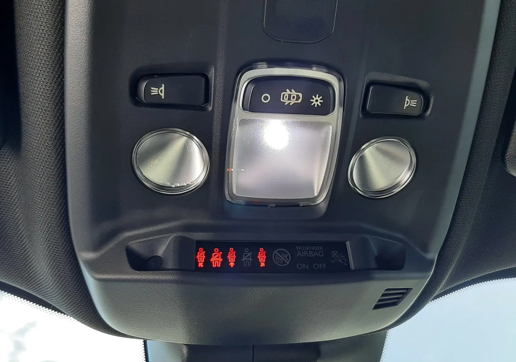 Vue en gros plan du plafonnier intérieur avec commandes d'éclairage et indicateurs de ceinture du Peugeot 2008 gris platinium 2023.