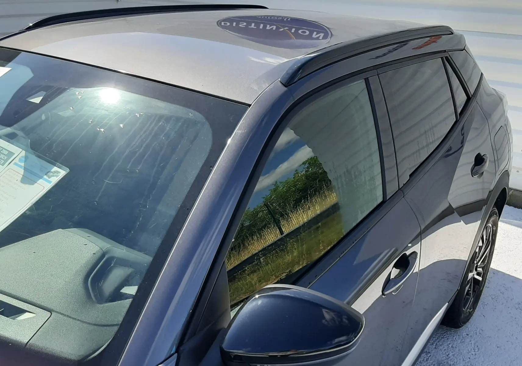 Vue plongeante sur le côté gauche d'un Peugeot 2008 gris platinium 2023 avec vitres teintées et rétroviseur noir.