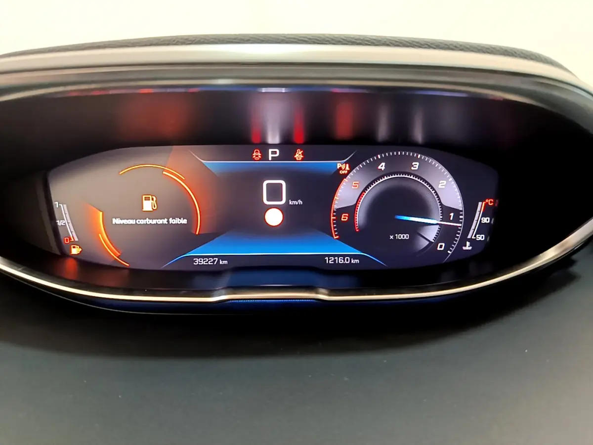 Tableau de bord numérique du Peugeot 3008 noir 2022 affichant vitesse zéro et avertissement niveau carburant faible.