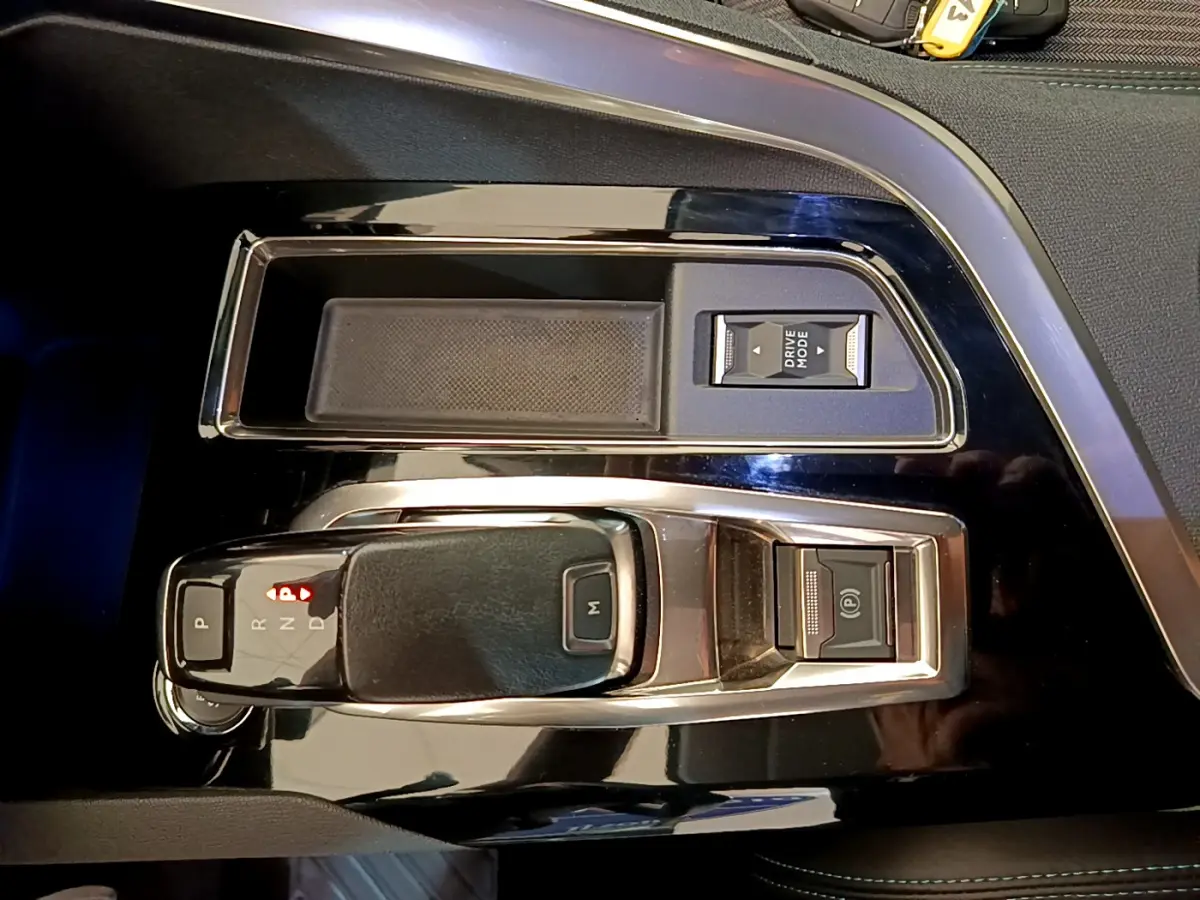 Vue rapprochée de la console centrale noire du Peugeot 3008 2022 avec levier de boîte auto et bouton Drive Mode.