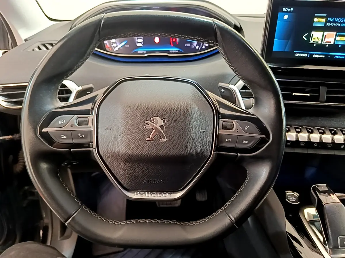 Vue rapprochée du volant cuir noir de la Peugeot 3008 2022 avec commandes intégrées et tableau de bord digital.