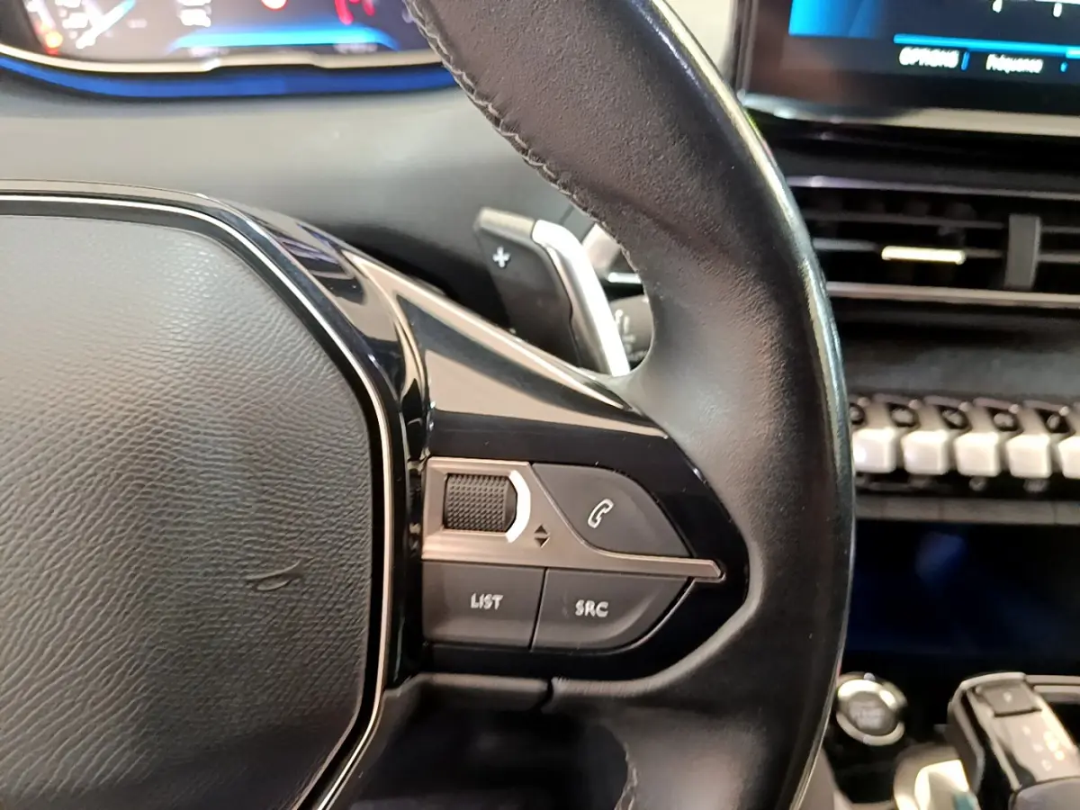 Gros plan sur le volant cuir noir de la Peugeot 3008 2022 avec commandes audio intégrées côté droit.