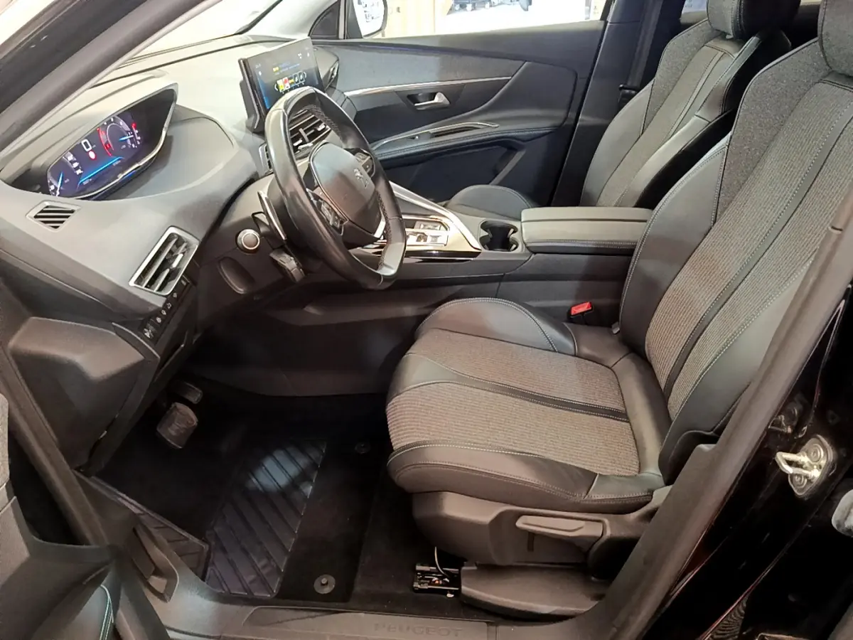 Intérieur côté conducteur du Peugeot 3008 noir 2022, avec tableau de bord numérique et sièges tissu-cuir gris.