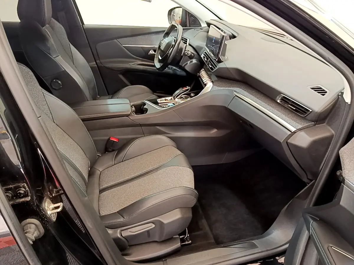 Intérieur avant droit du Peugeot 3008 noir 2022, sièges tissu et cuir, tableau de bord moderne avec écran tactile central.