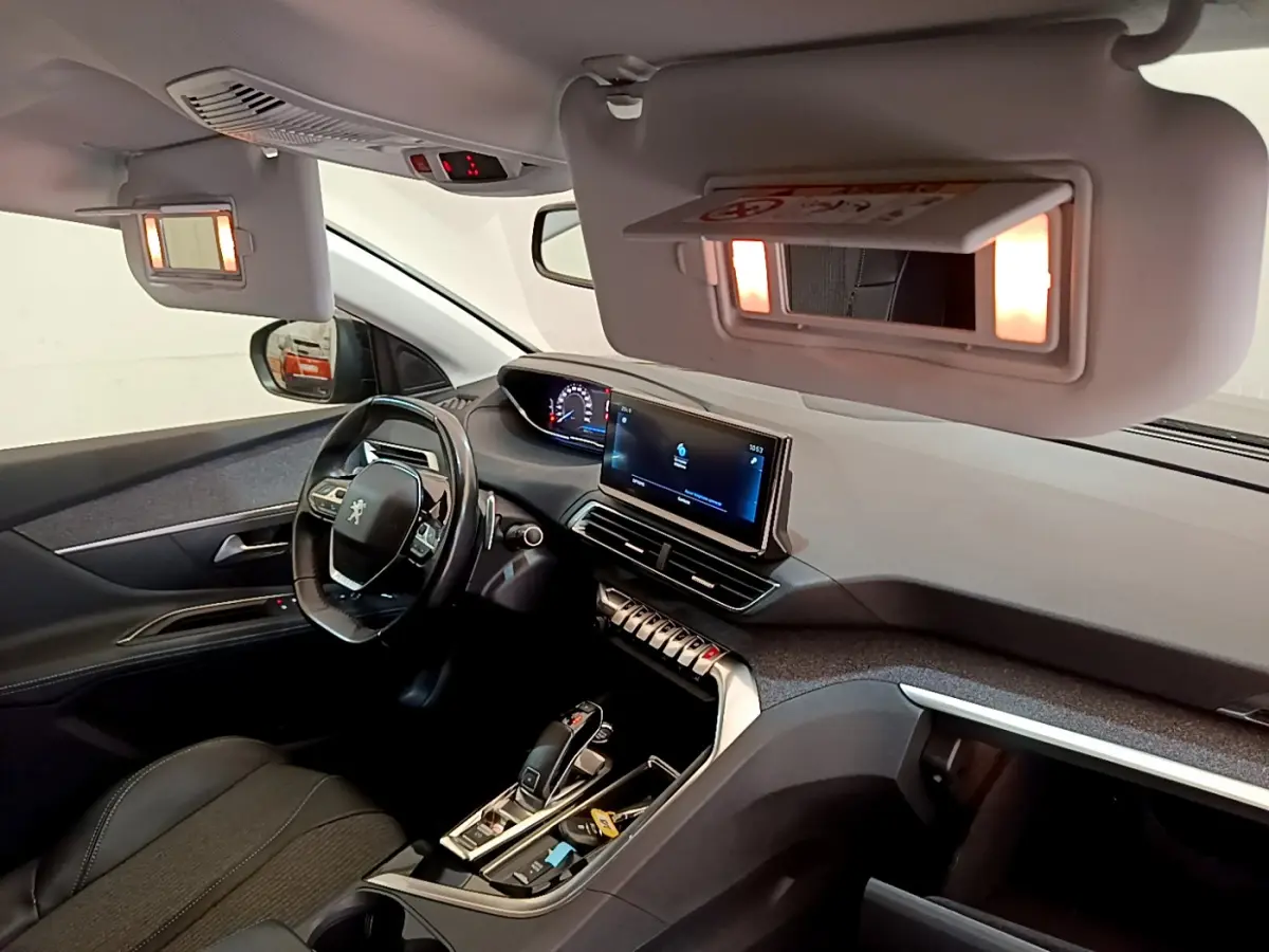 Intérieur du Peugeot 3008 2022 vu côté conducteur, tableau de bord moderne avec écran tactile allumé et volant cuir noir.