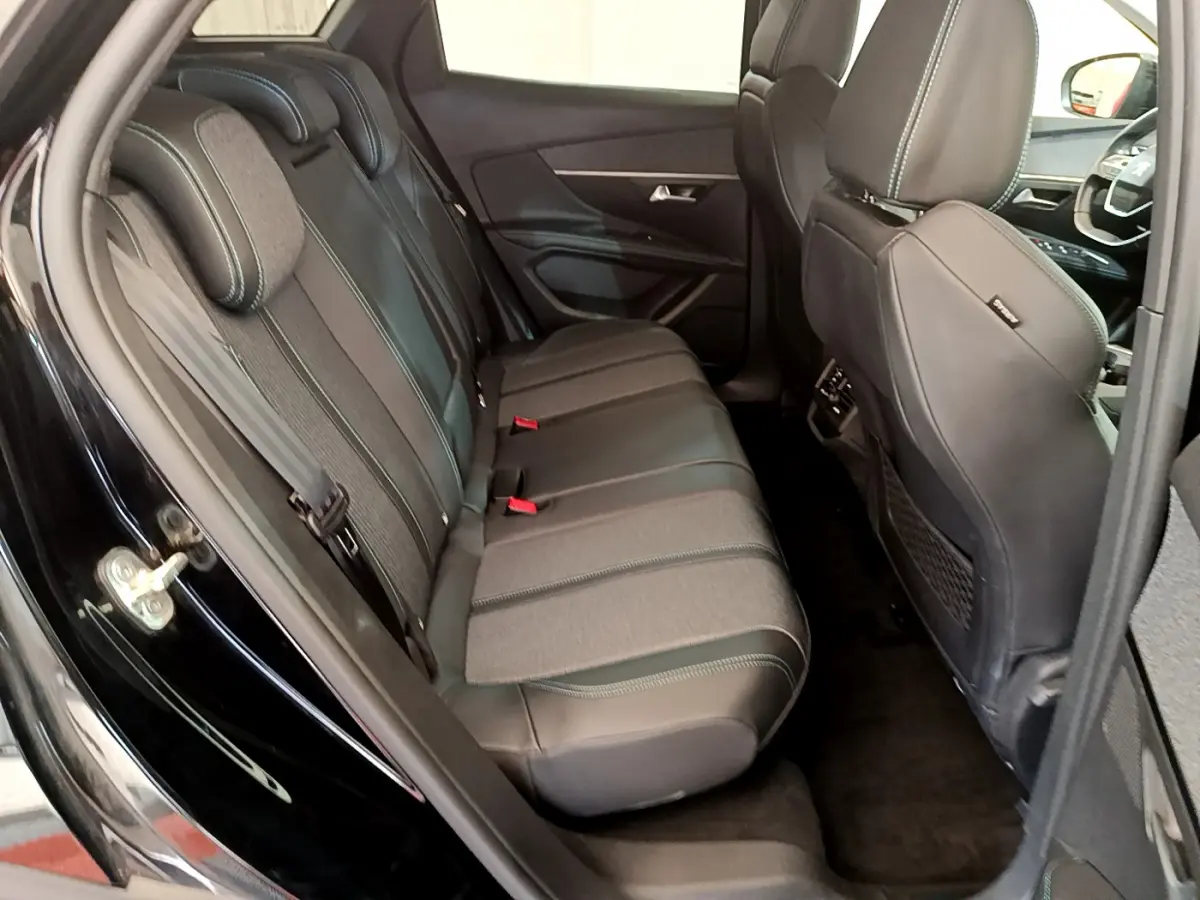 Vue intérieure côté gauche sur la banquette arrière en cuir et tissu du Peugeot 3008 noir, avec sièges avant partiellement visibles.