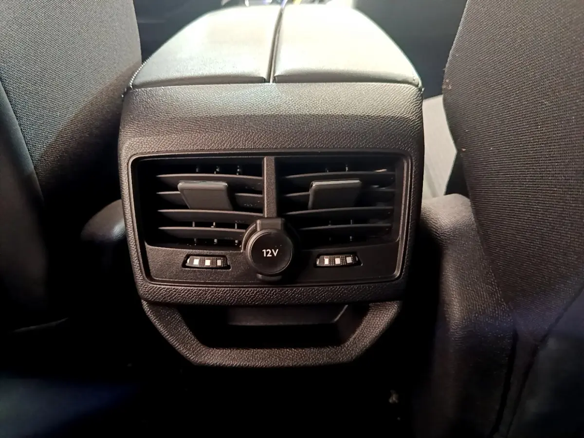 Gros plan sur la prise 12V et les aérateurs arrière noirs entre les sièges du Peugeot 3008 noir 2022.