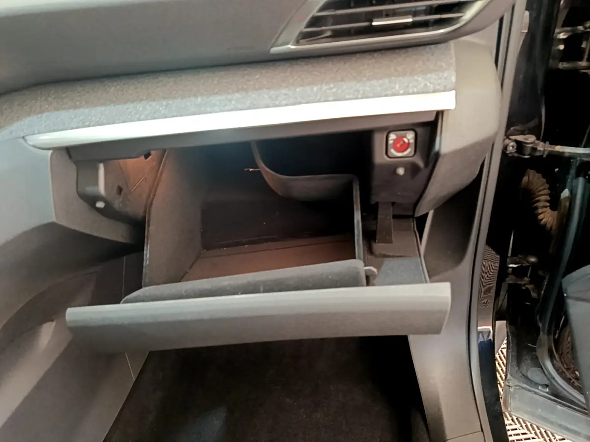 Vue intérieure côté passager du Peugeot 3008 noir 2022, boîte à gants ouverte avec éclairage intérieur visible