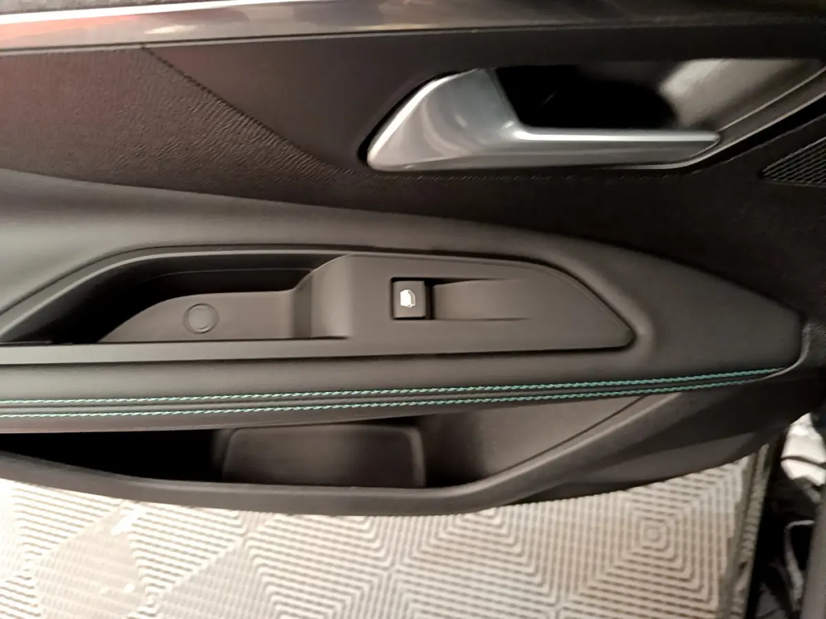 Gros plan sur la poignée intérieure côté gauche de la porte noire du Peugeot 3008 avec surpiqûres bleues.