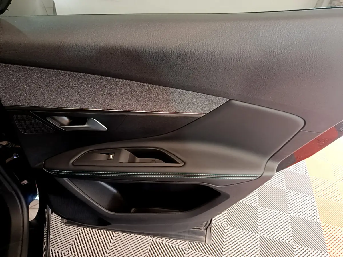 Gros plan sur la porte intérieure côté gauche du Peugeot 3008 noir, avec poignée et commandes de vitre intégrées.