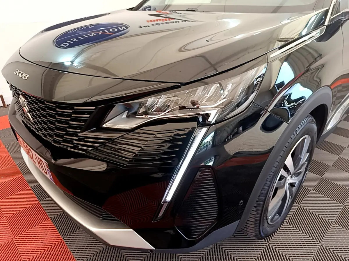 Vue 3/4 avant droit d'un Peugeot 3008 noir avec phares LED et calandre distinctive en intérieur showroom.