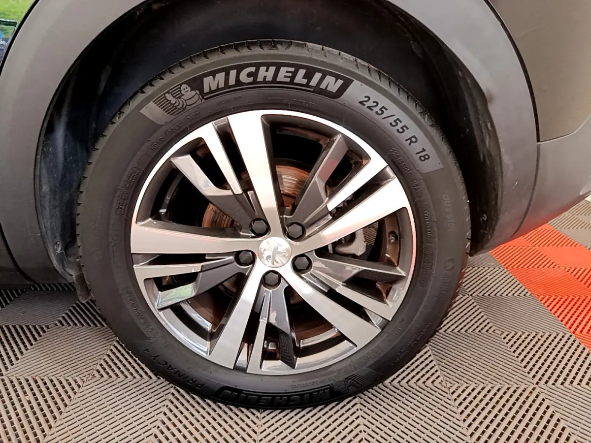 Gros plan sur la roue avant droite du Peugeot 3008 noir, mettant en valeur la jante alliage et le pneu Michelin.