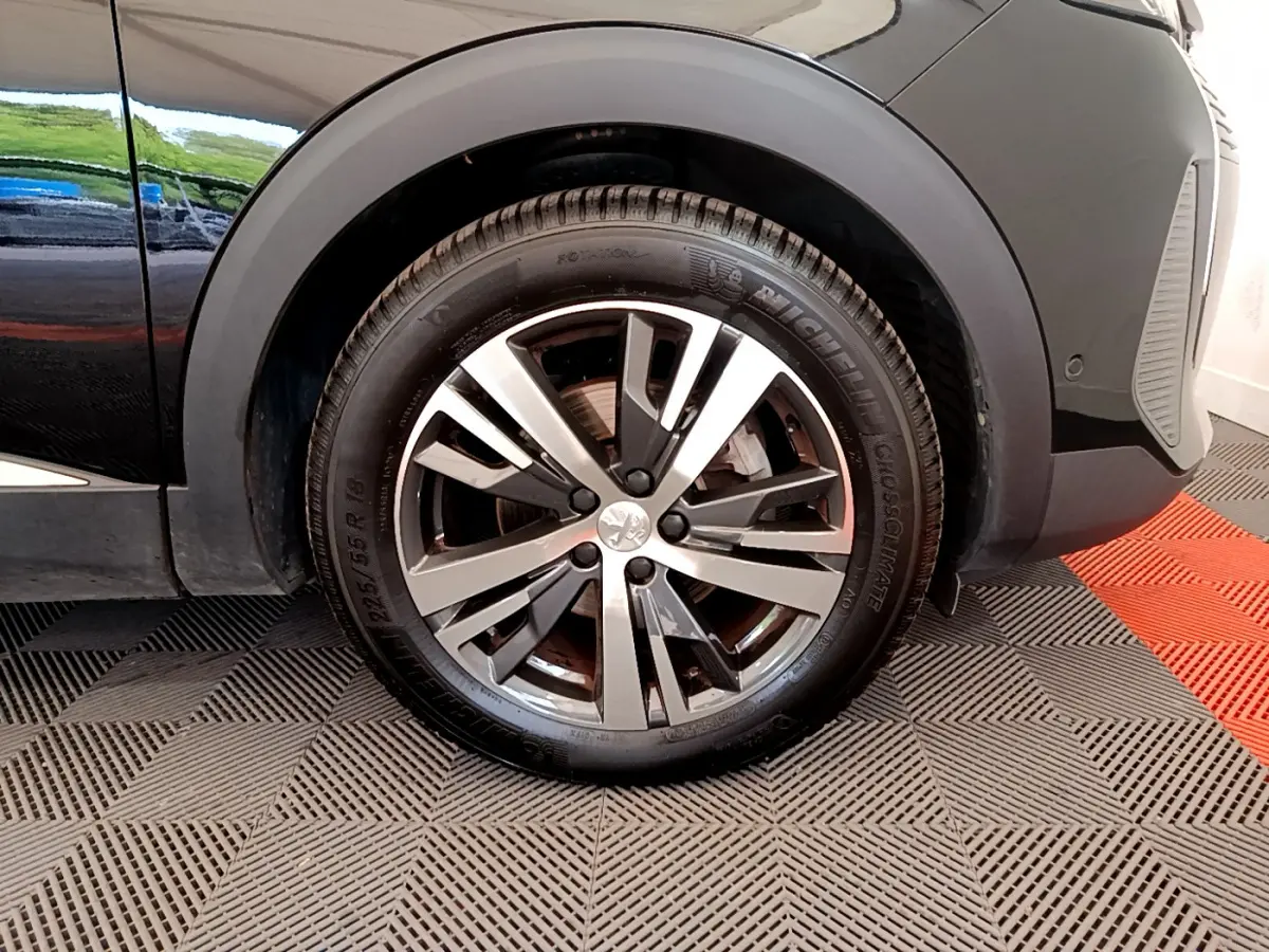 Gros plan sur la roue avant gauche du Peugeot 3008 noir, mettant en valeur la jante alliage et le pneu Michelin.