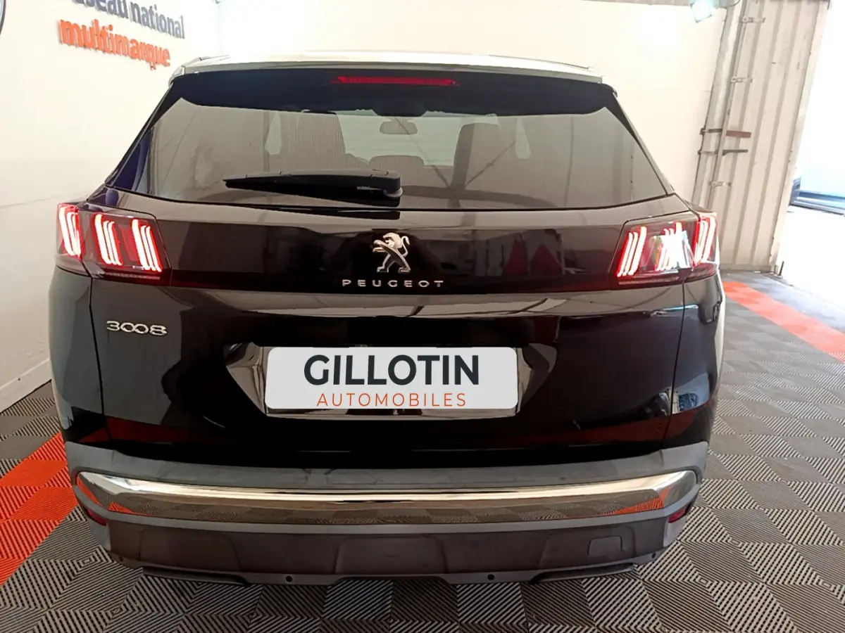 Vue arrière d'un Peugeot 3008 noir avec feux LED caractéristiques et logo central dans un garage.