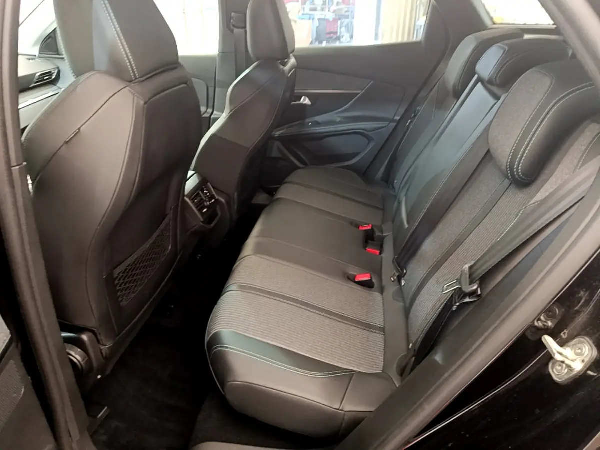 Vue côté droit de l'intérieur arrière du Peugeot 3008 noir 2022 avec sièges en cuir et tissu gris à surpiqûres blanches.