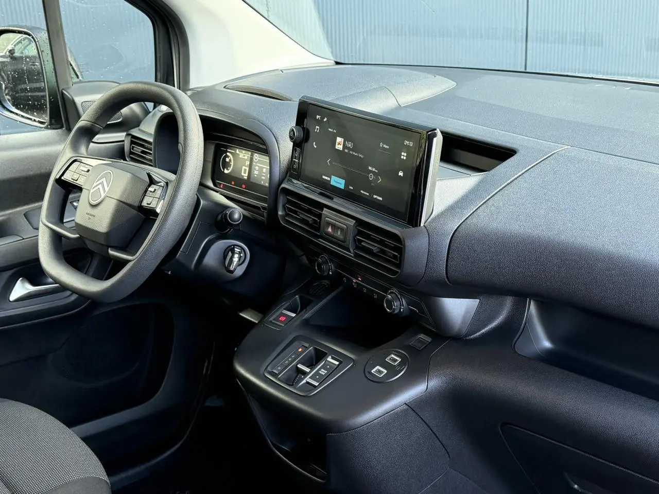 Intérieur du Citroën Berlingo 2025 vu côté conducteur, tableau de bord noir avec écran tactile 10 pouces central.