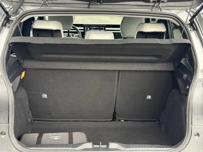 Coffre ouvert vu de l'arrière d'une Citroën C3 électrique 2025 gris Mercury, avec banquette arrière et tablette de coffre visible.