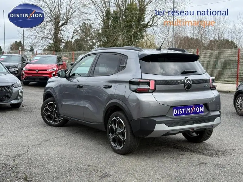 Vue 3/4 arrière droite d'une Citroën C3 électrique 2025 gris Mercury avec jantes noires et détails noirs contrastants.