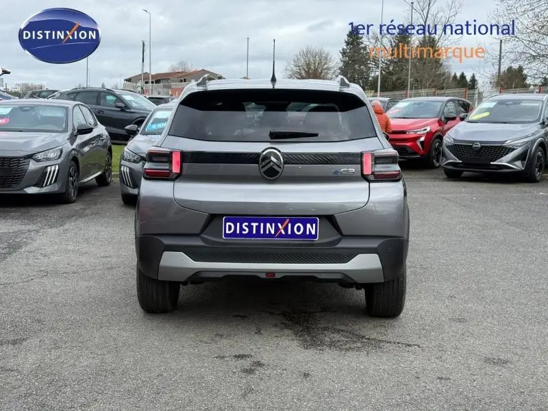 Vue arrière d'une Citroën C3 électrique 2025 gris Mercury avec logo central et feux arrière rectangulaires allumés.