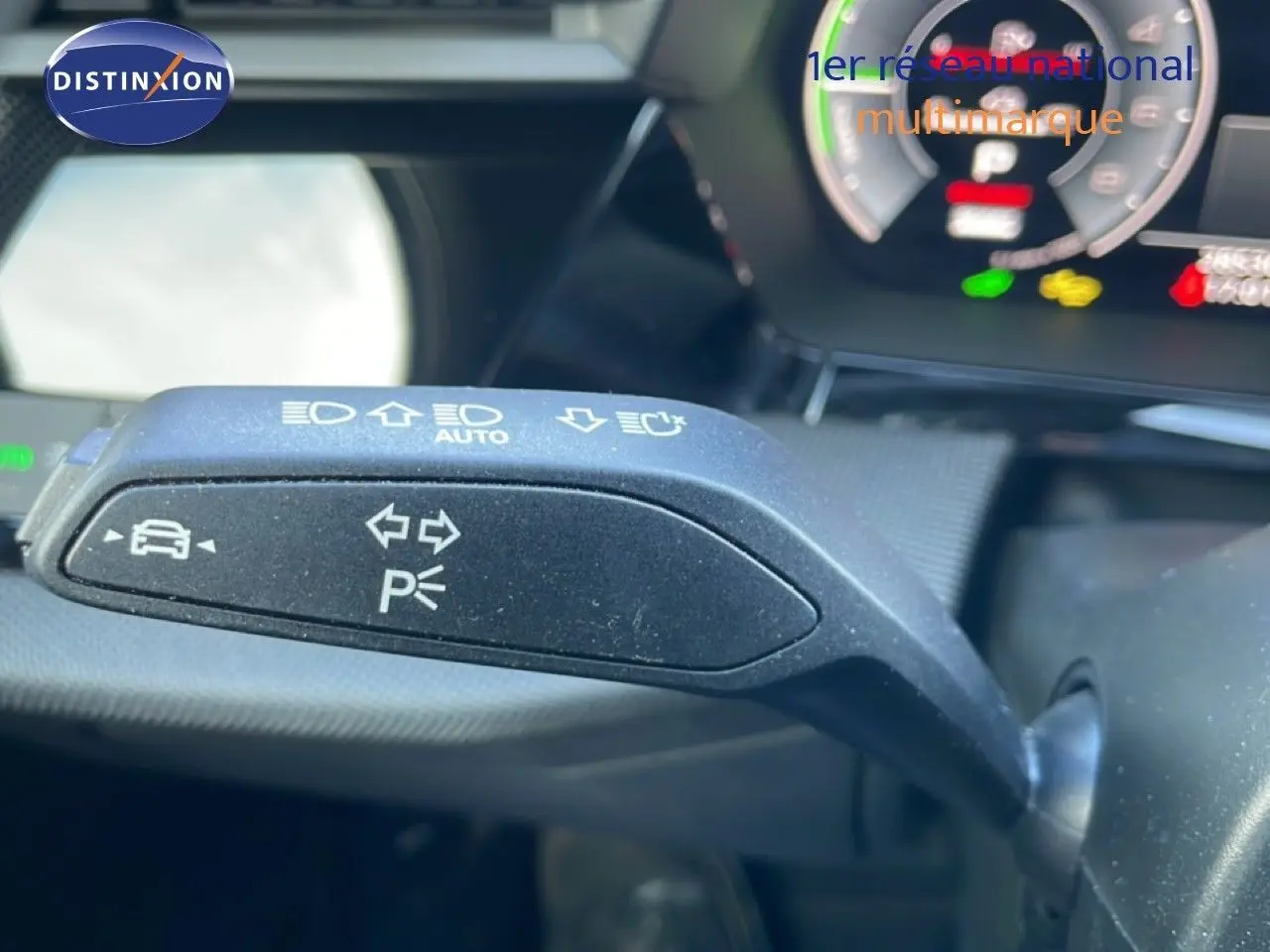 Gros plan sur la commande de clignotants et feux automatiques à gauche du volant dans l'Audi A3 Sportback blanc ibisé 2025.