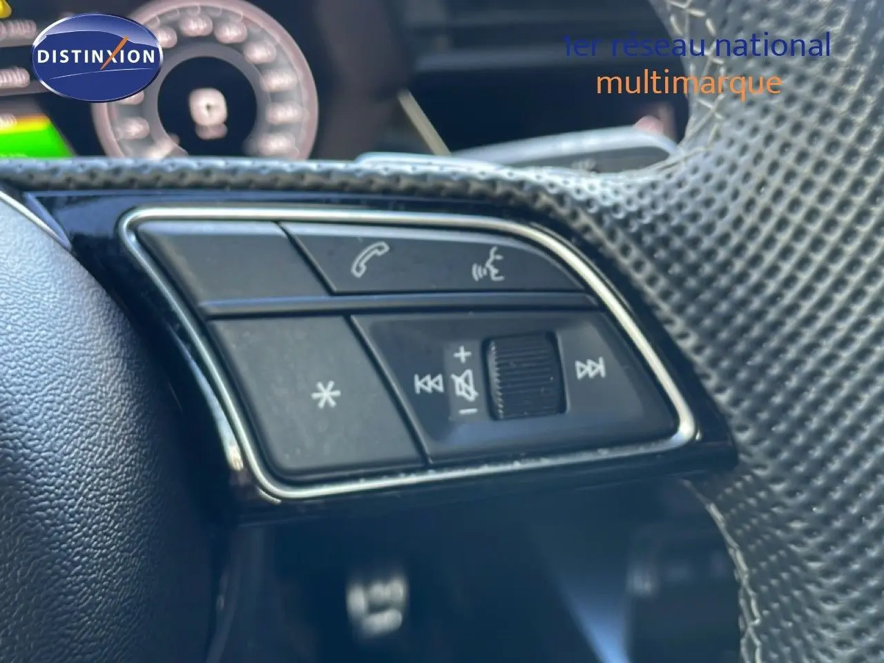 Gros plan sur les commandes du volant à droite de l'Audi A3 Sportback 40 TFSIe blanc Ibis, intérieur gris-noir.