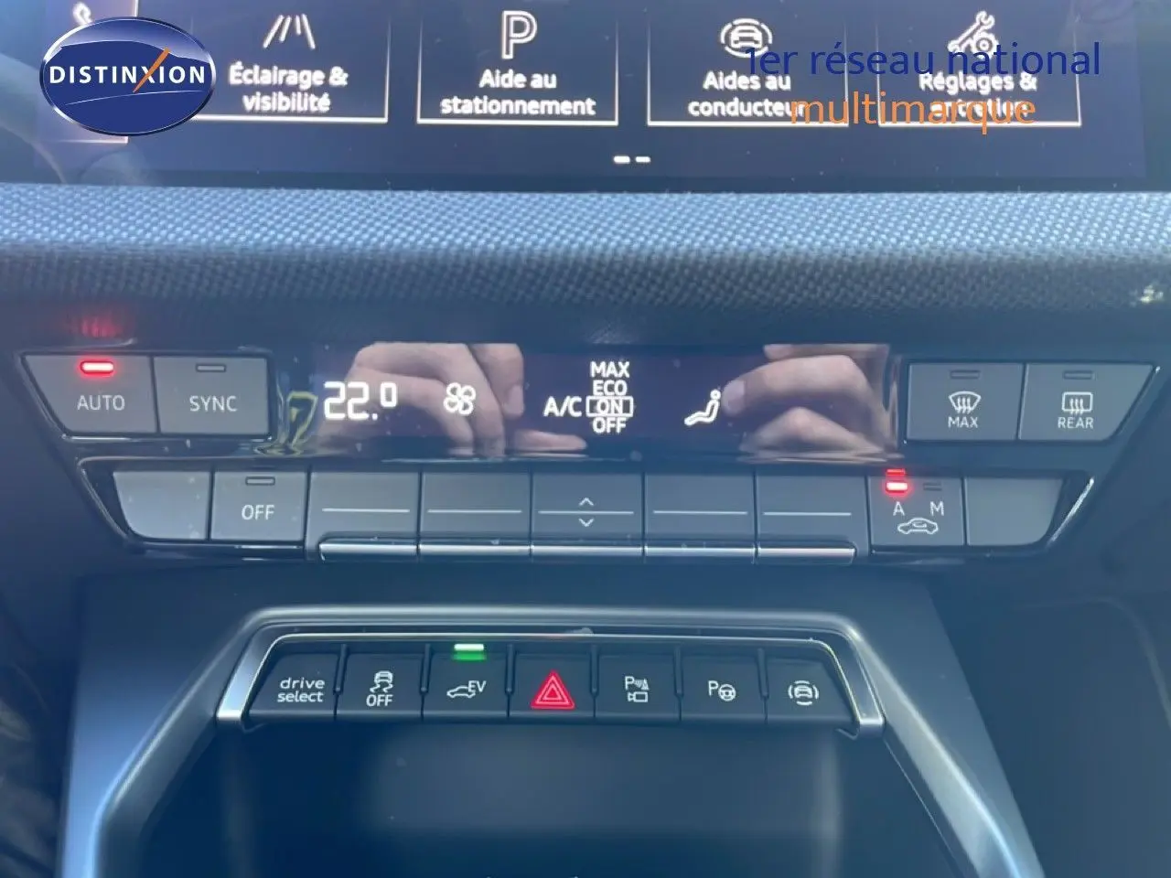 Gros plan sur la console centrale de l’Audi A3 Sportback blanc Ibis 2025, mettant en valeur les commandes climatisation et aides à la conduite.