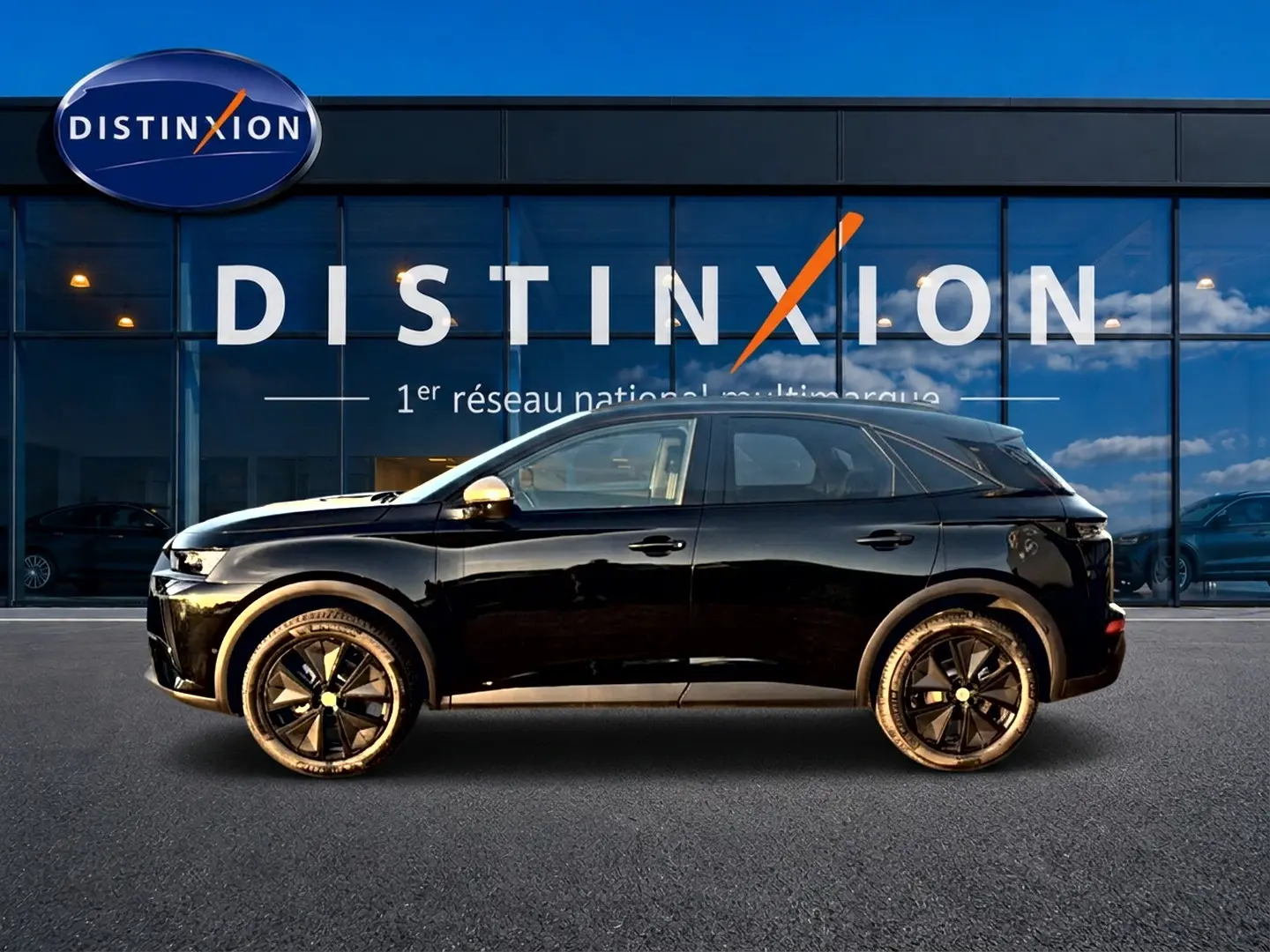 Vue de profil côté gauche d'un DS7 noir 2026 garé devant une vitrine avec logo Distinxion.